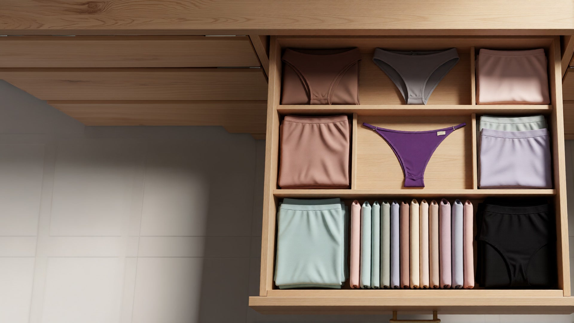 Wooden drawer with organized women's underwear and socks on a neutral background